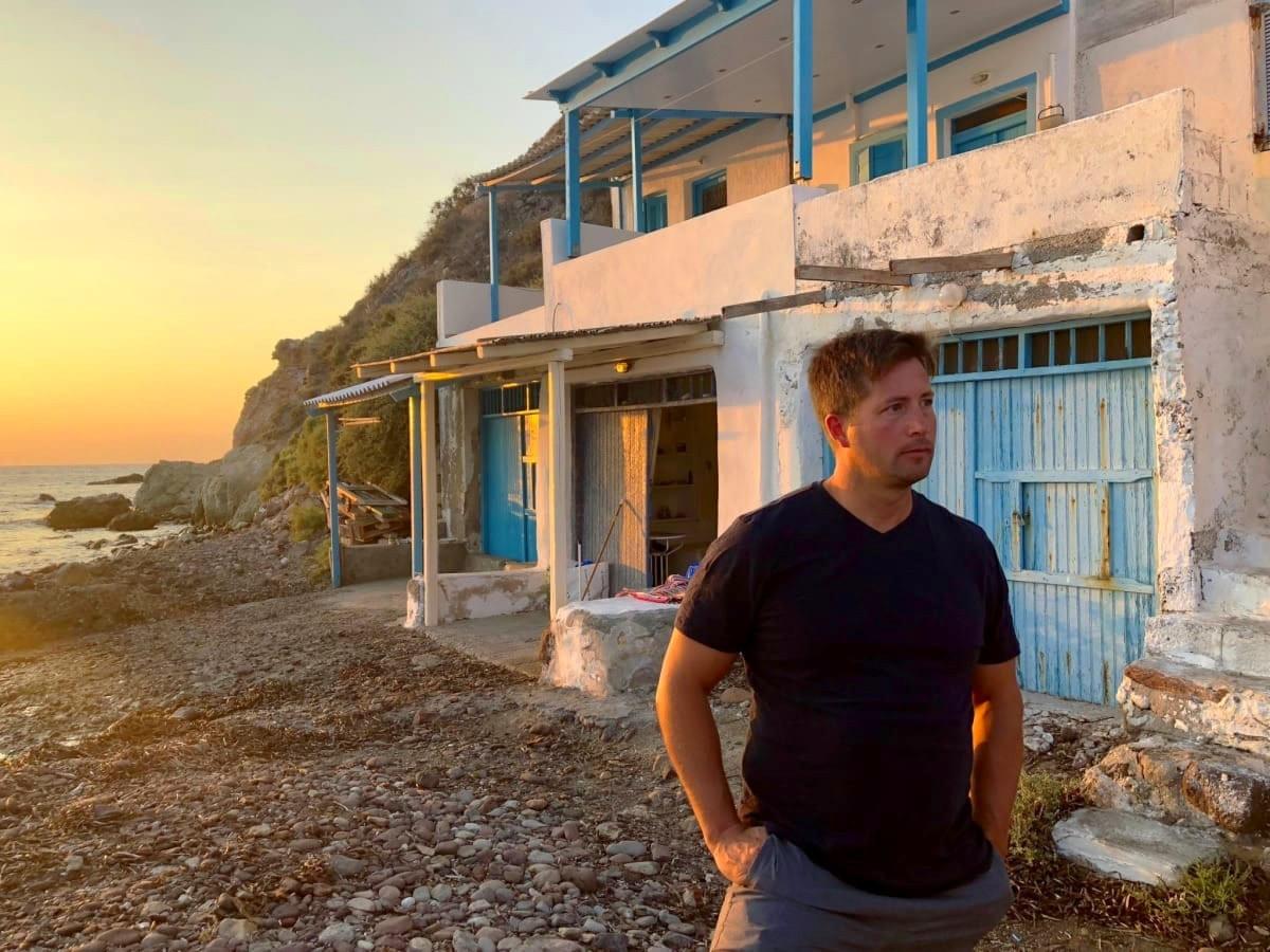 Man stands in front a syrma at sunset in Klima, Milos, Greece Man stands in front a syrma at sunset in Klima, Milos, Greece