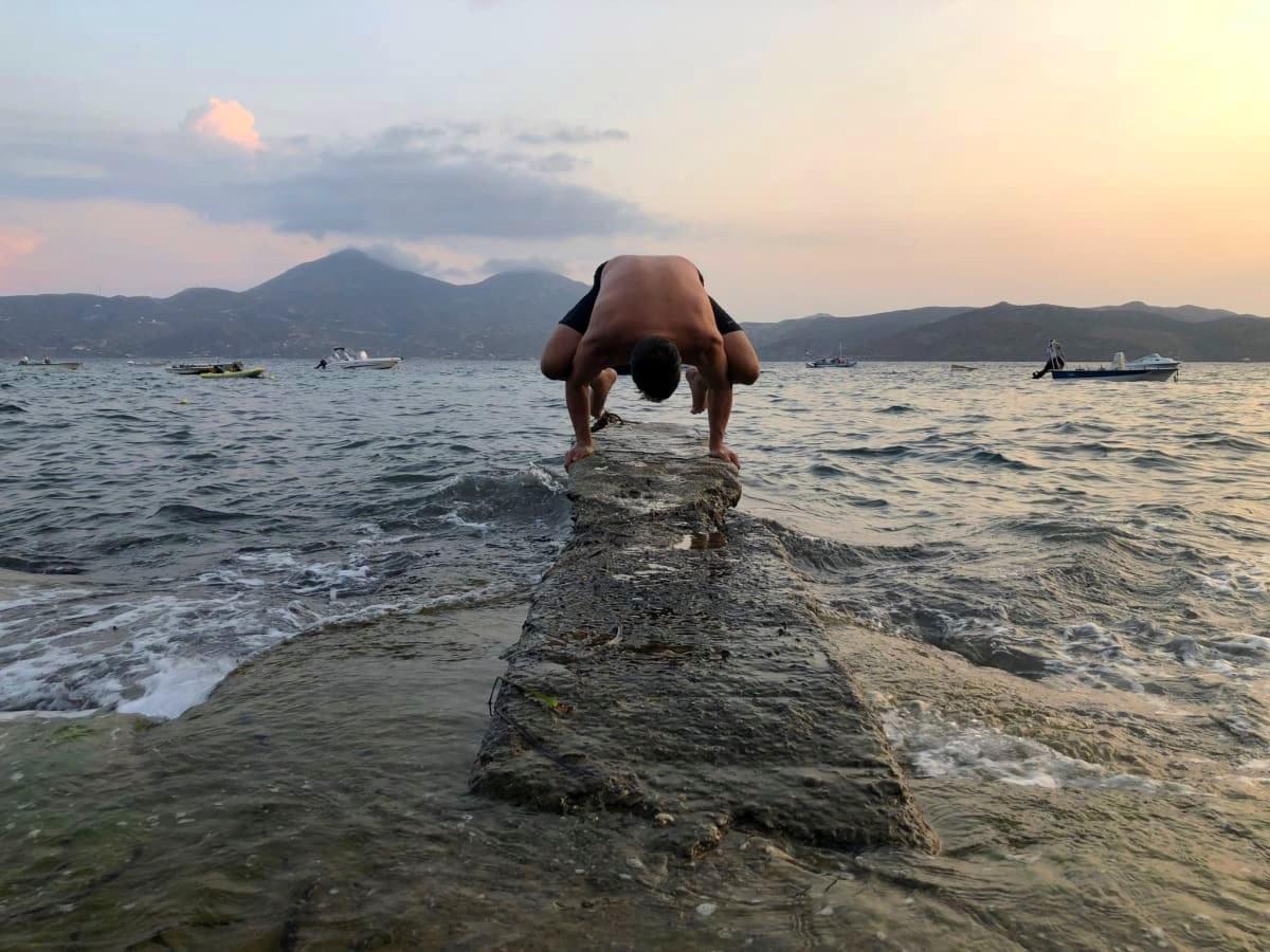 Man practices yoga on a pier in the sea in Klima, Milos Man practices yoga on a pier in the sea in Klima, Milos
