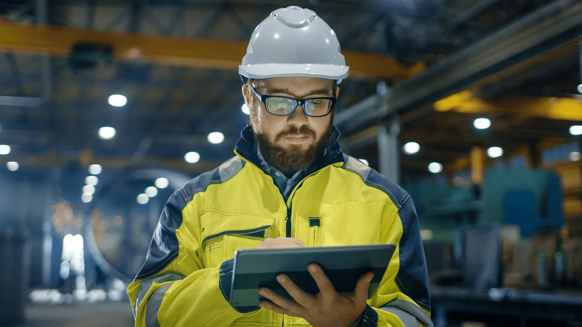 manufacturing worker in safety equipment reviewing online learning with tablet manufacturing worker in safety equipment reviewing online learning with tablet