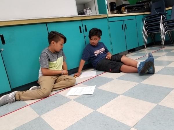 two boys work together on classroom floor two boys work together on classroom floor