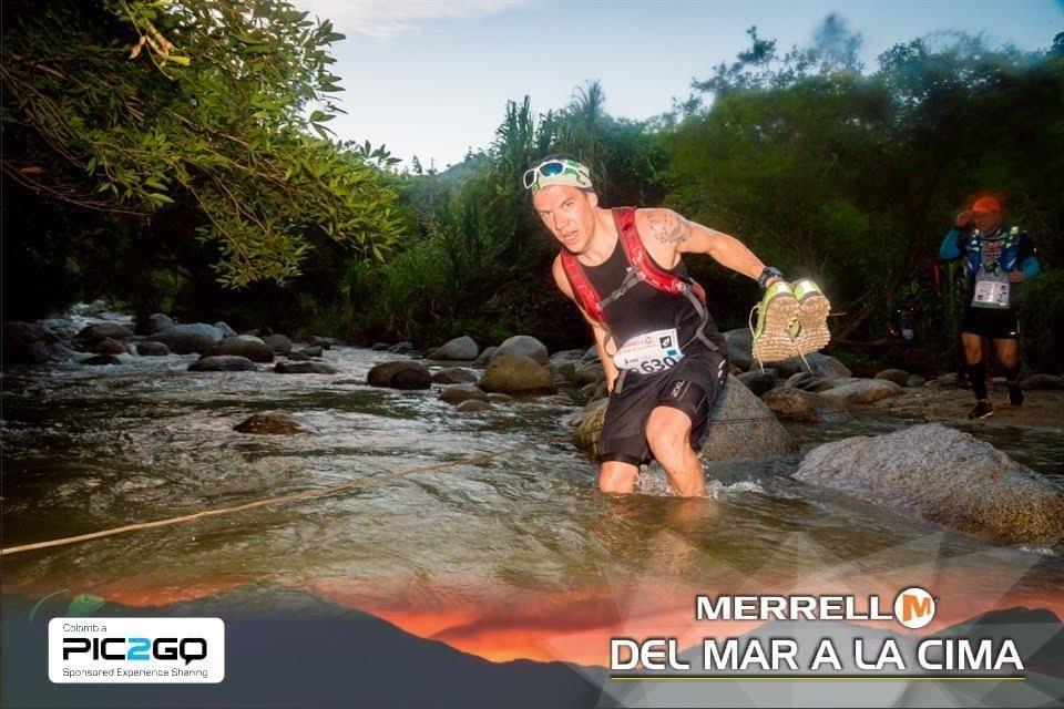 A runner holds his shoes as he makes a river crossing at Del Mar a La Cima ultra marathon A runner holds his shoes as he makes a river crossing at Del Mar a La Cima ultra marathon