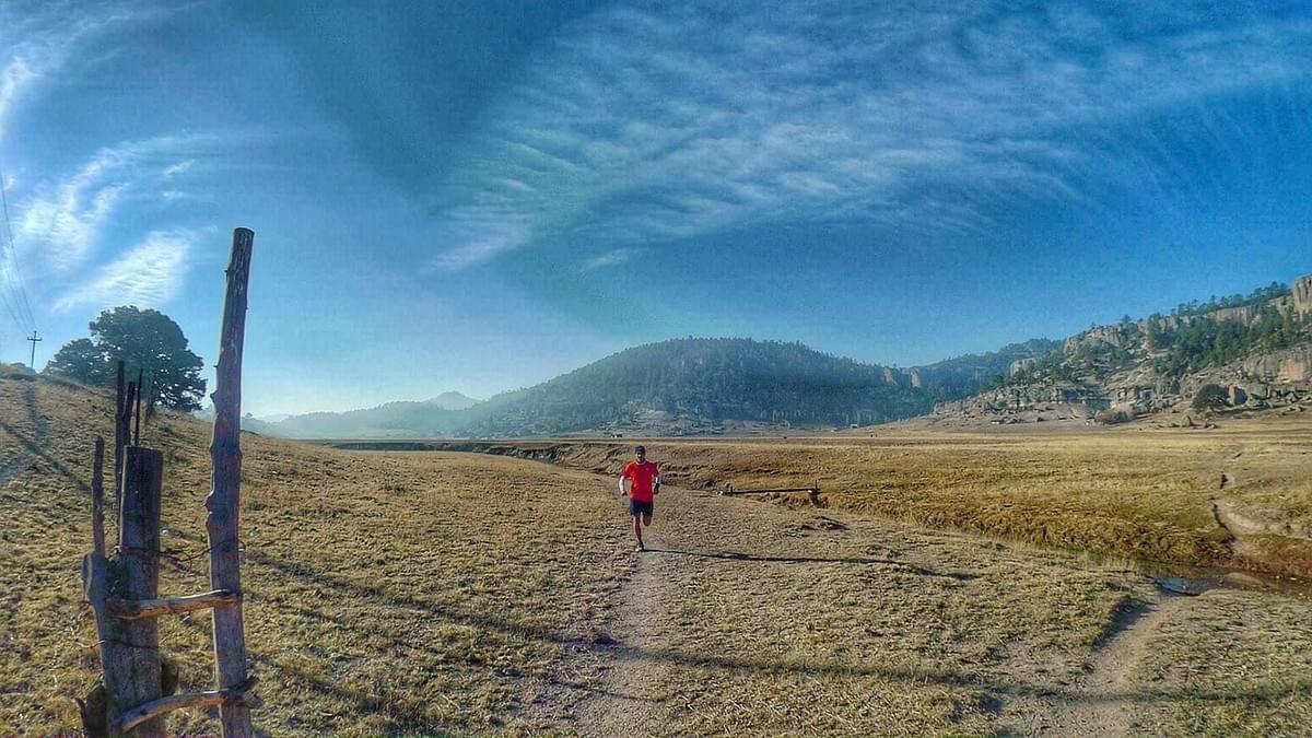 A trail runner following a narrow track through plains in the Sierra Tarahamura. Mexico A trail runner following a narrow track through plains in the Sierra Tarahamura. Mexico