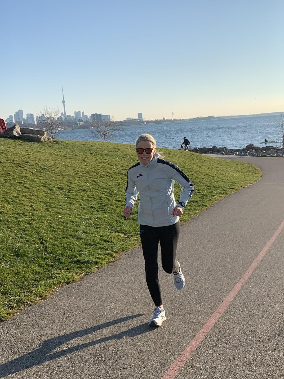 a female runner running along the Toronto waterfront trail with Toronto skyline behind her a female runner running along the Toronto waterfront trail with Toronto skyline behind her