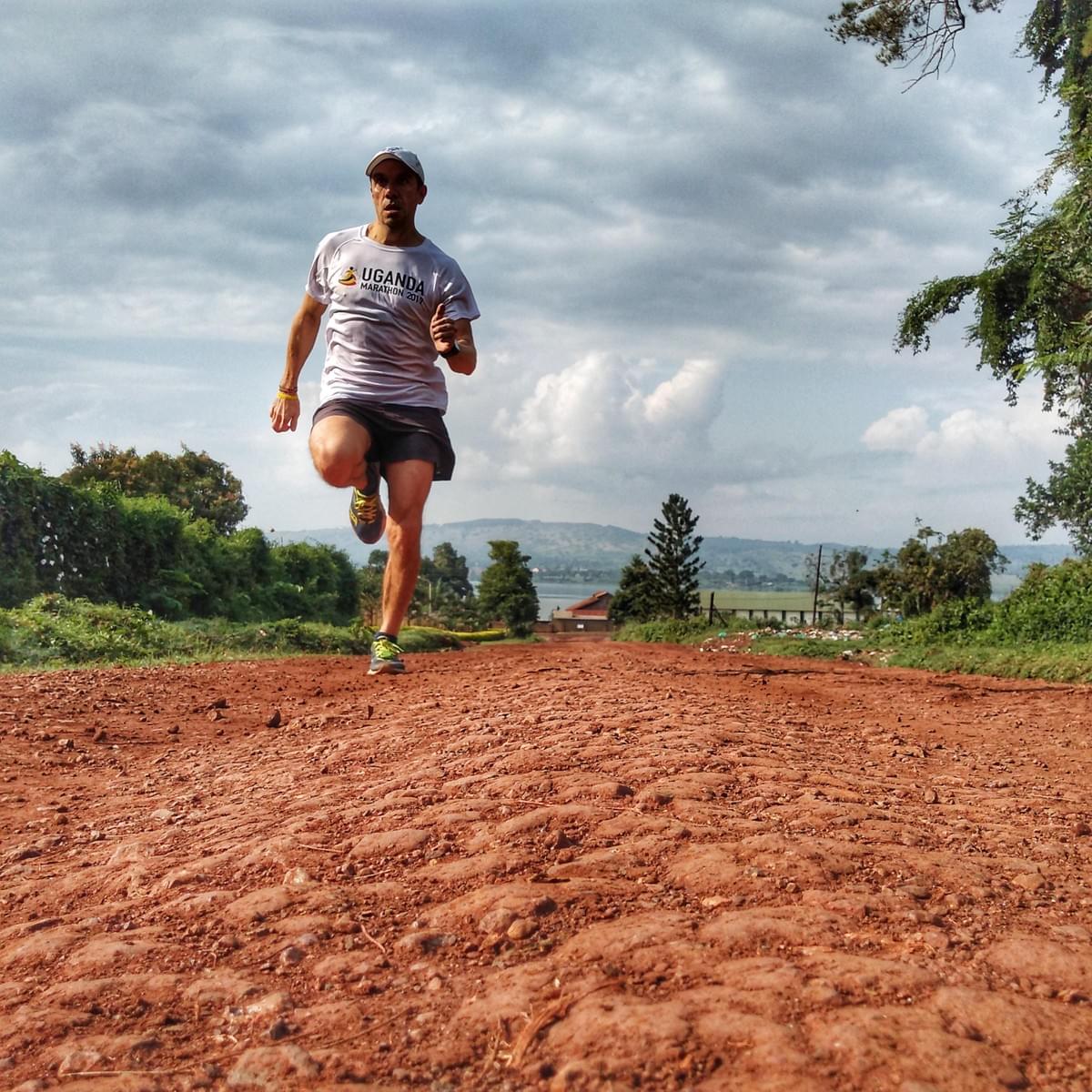 Runner climbing a red dirt road with the source of the Nile in Jinja, Uganda in the background Runner climbing a red dirt road with the source of the Nile in Jinja, Uganda in the background