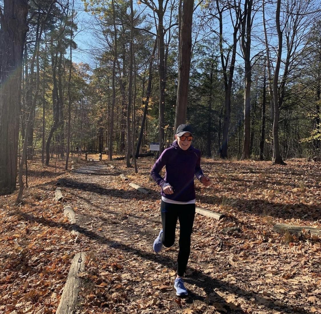 a female runner is running through a Toroto woodland running trail during fall a female runner is running through a Toroto woodland running trail during fall