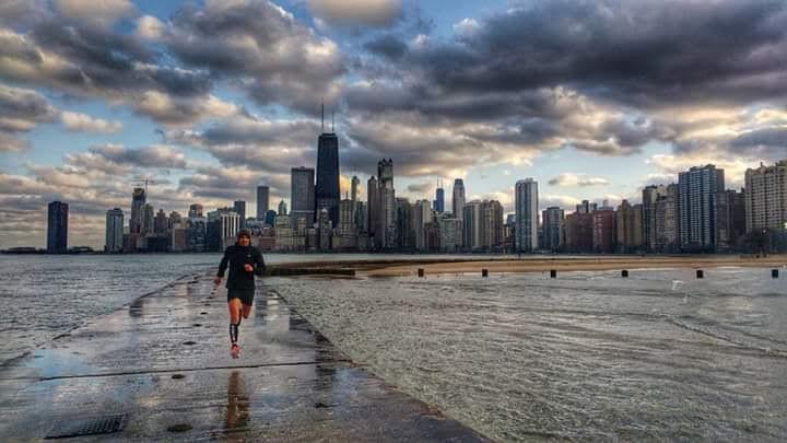 A runner runs along a pier onto Lake Michigan on a freezing morning. Chicago skyline in the background. A runner runs along a pier onto Lake Michigan on a freezing morning. Chicago skyline in the background.