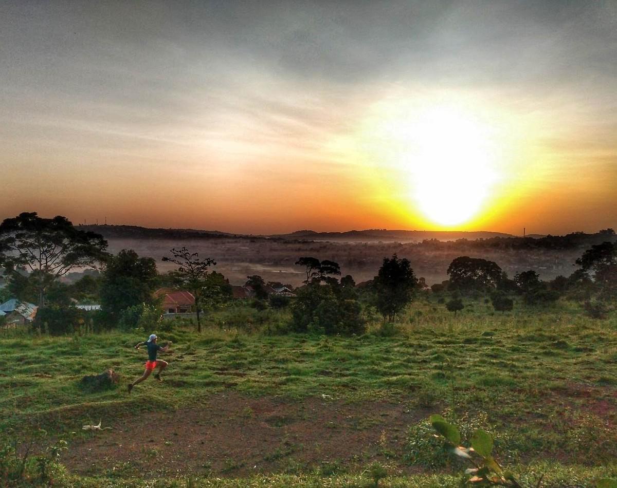 A runner moves across a bumpy meadow during a spectacular sunrise run above a misty Masaka, Uganda A runner moves across a bumpy meadow during a spectacular sunrise run above a misty Masaka, Uganda