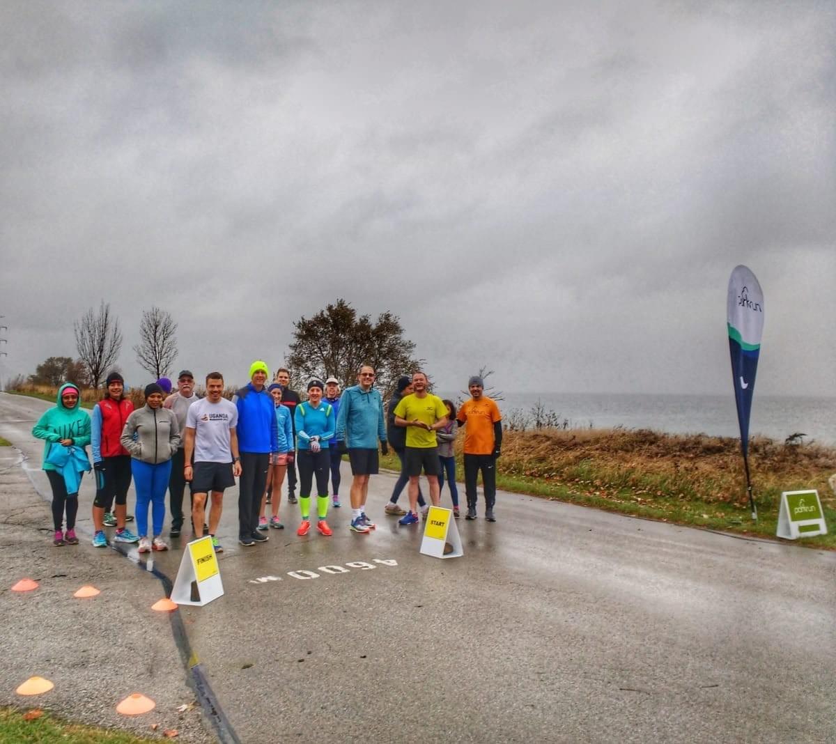 A group of well-wrapped runners gather at the start line of Beach Strip parkrun, Hamilton beside a cloudy Lake Ontario A group of well-wrapped runners gather at the start line of Beach Strip parkrun, Hamilton beside a cloudy Lake Ontario