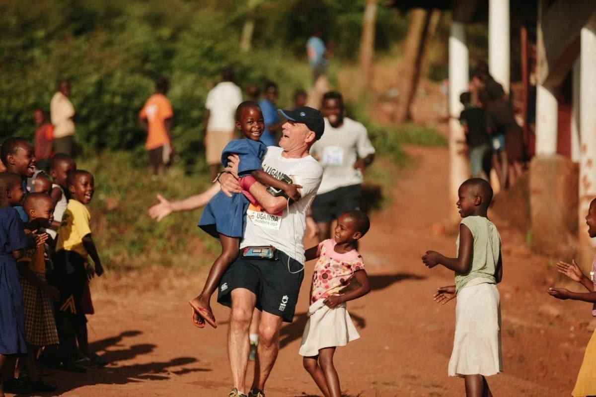 A Uganda Marathon runner celebrates with a local child on the race course A Uganda Marathon runner celebrates with a local child on the race course
