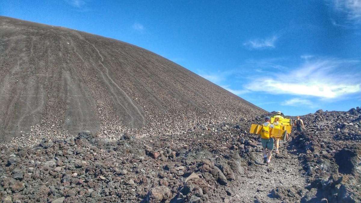 A Quetzaltrekkers group carry volcano boards on their backs whilst hiking a path beside Cerro Negro, Nicaragua A Quetzaltrekkers group carry volcano boards on their backs whilst hiking a path beside Cerro Negro, Nicaragua