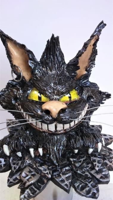 'Oil' effect glaze on free standing Cheshire cat. Head is 7" x 7" and 8" wide across leaf effect base. Earthenware clay 'Oil' effect glaze on free standing Cheshire cat. Head is 7" x 7" and 8" wide across leaf effect base. Earthenware clay