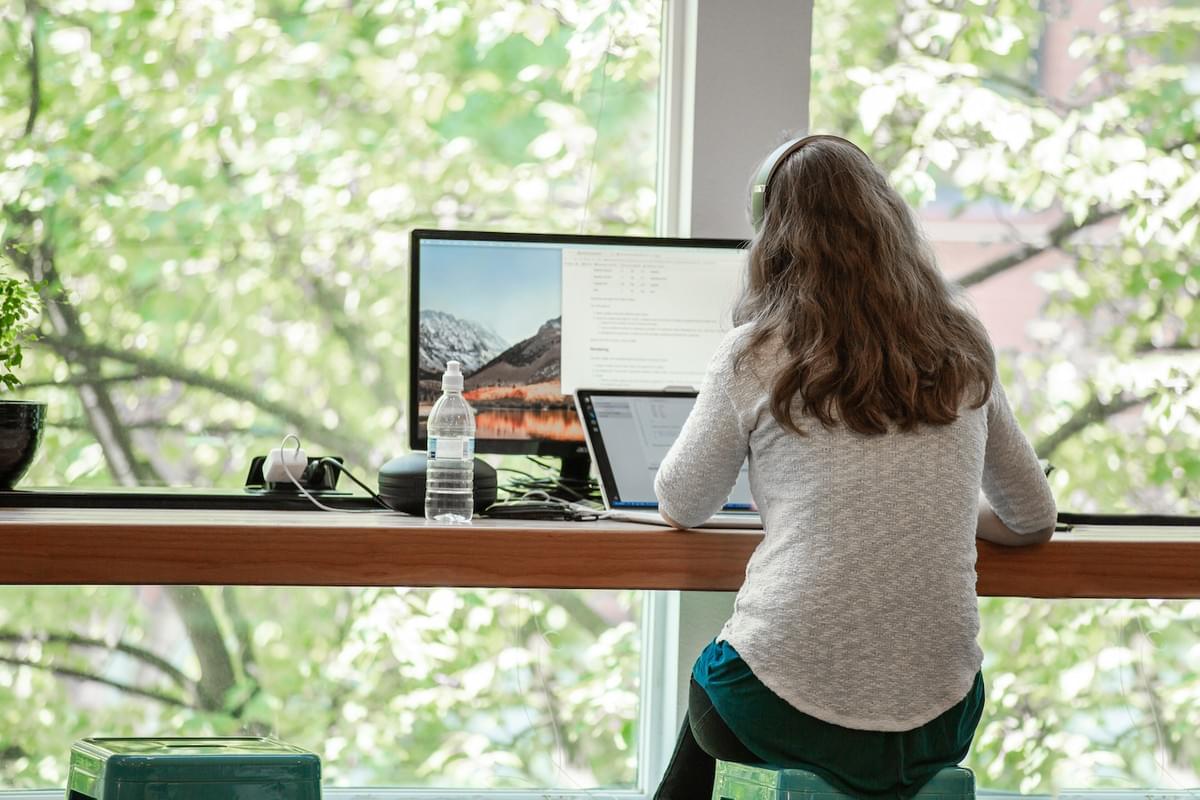 Student with headphones working on code at counter by window Student with headphones working on code at counter by window