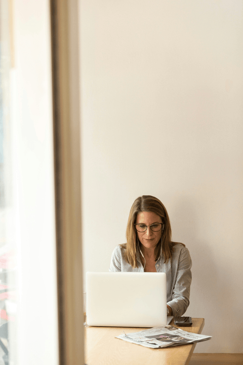 Mujer rubia usando una computadora en un escritorio.