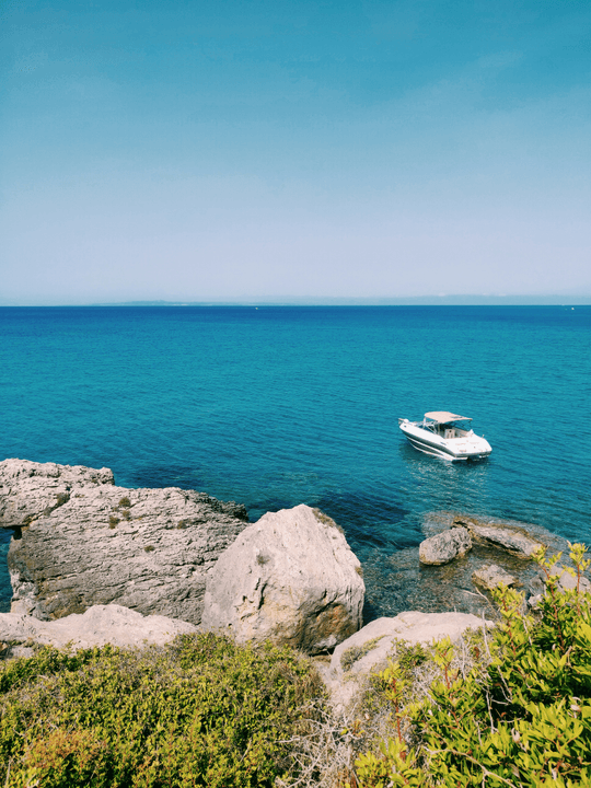 Small boats floating on turquoise sea near rocky shore