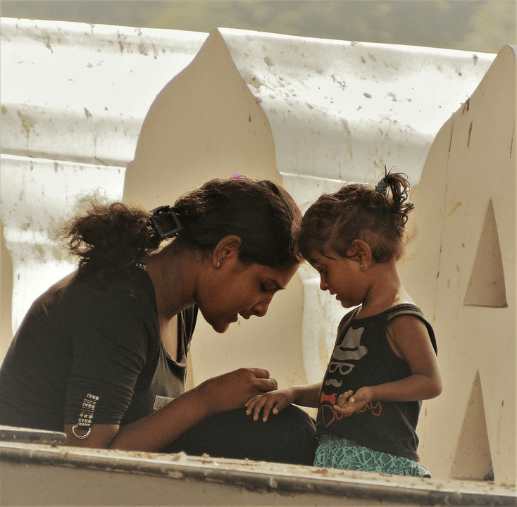 Mother sitting on the roadside, engaging in a heartfelt conversation with her toddler daughter