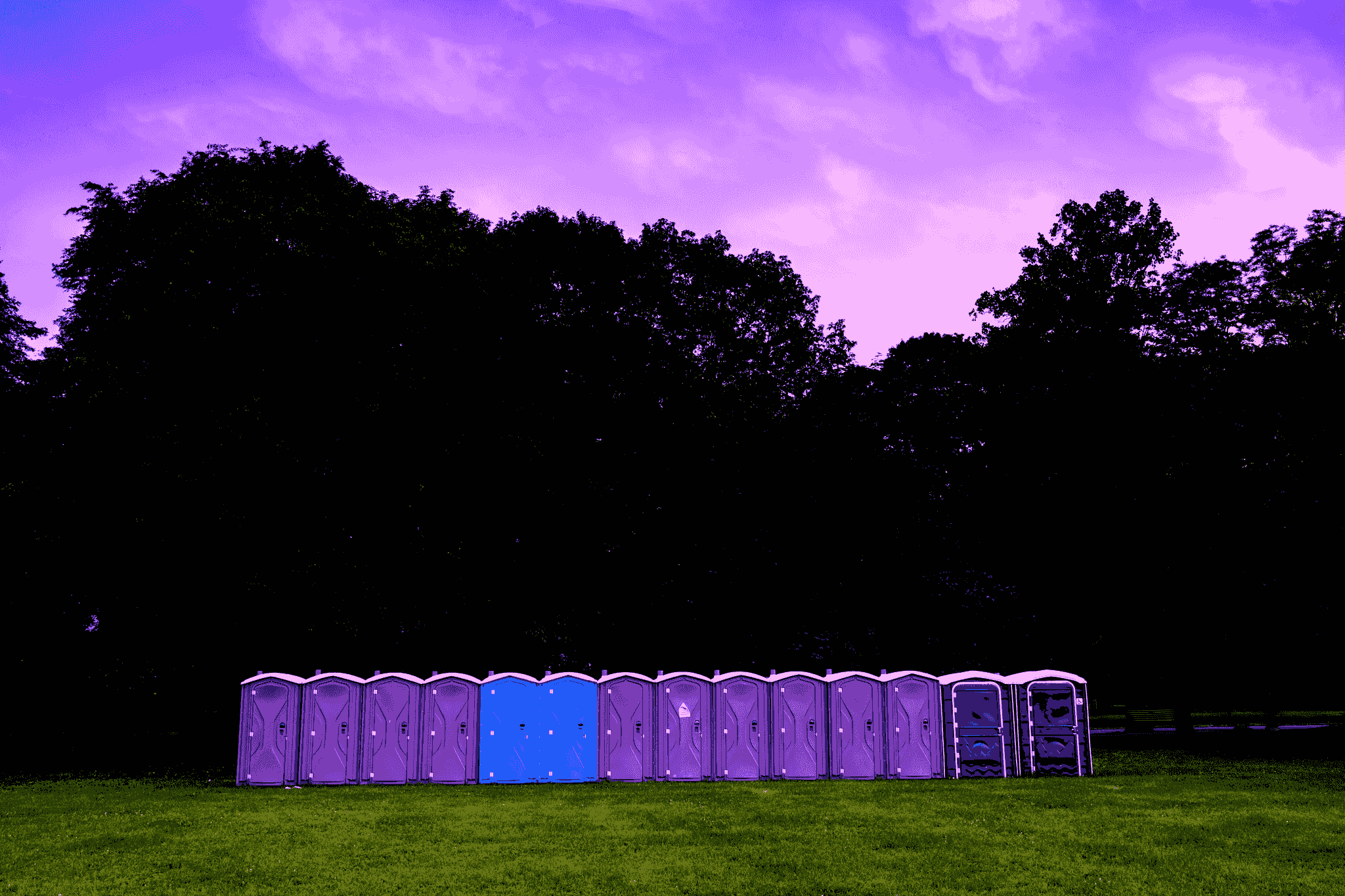 Colorful portable toilet units at an outdoor venue.