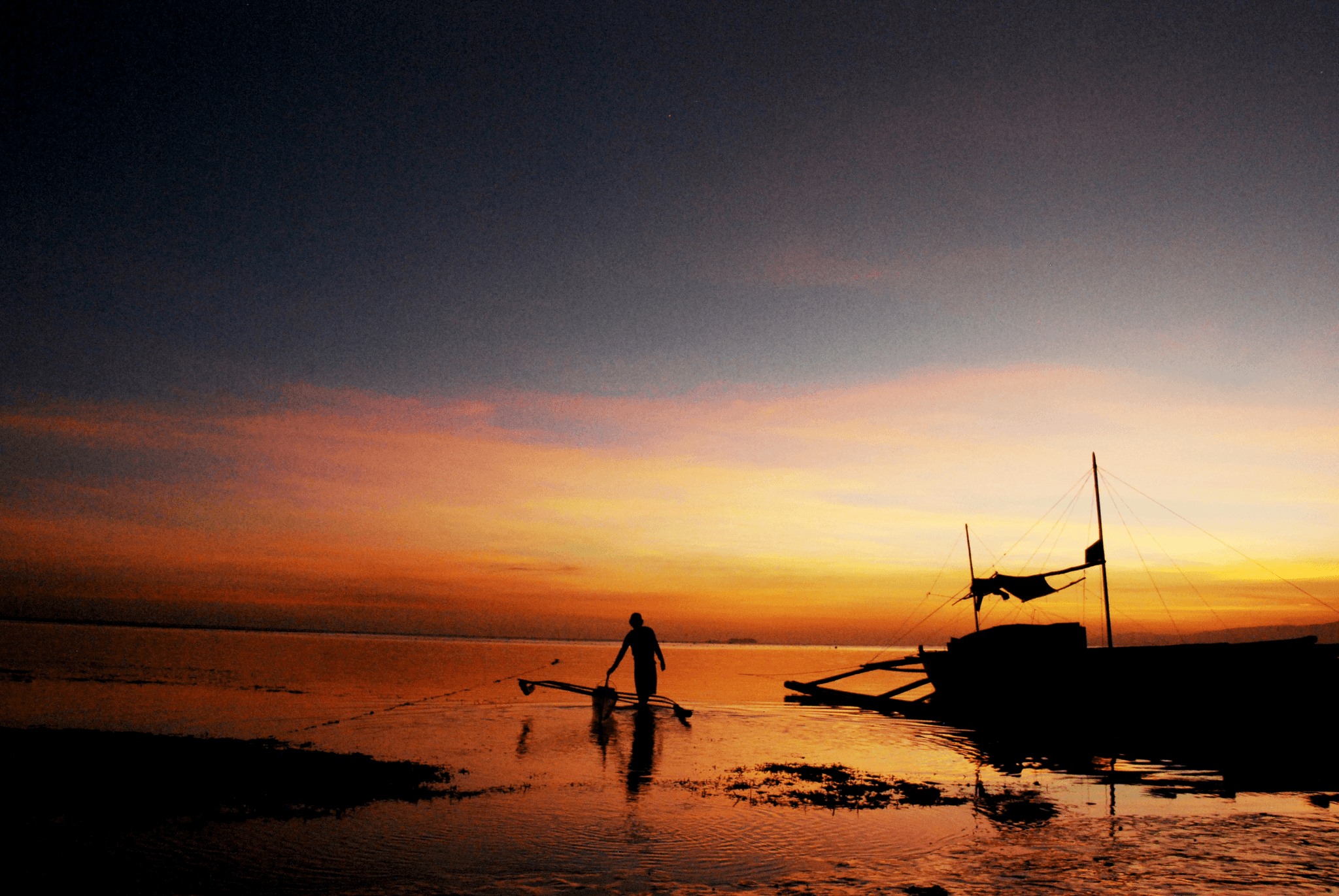 Fishermen in a small aluminum fishing boat at sunset