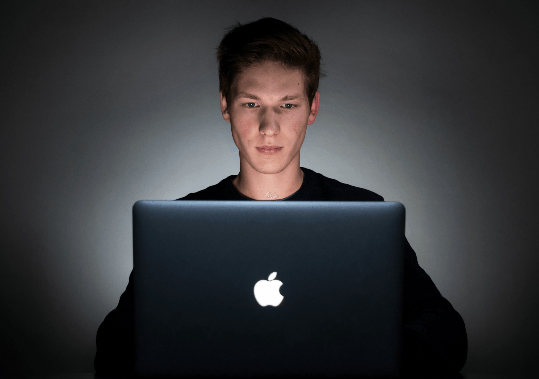 Image of white male looking at the screen of a Apple laptop computer.