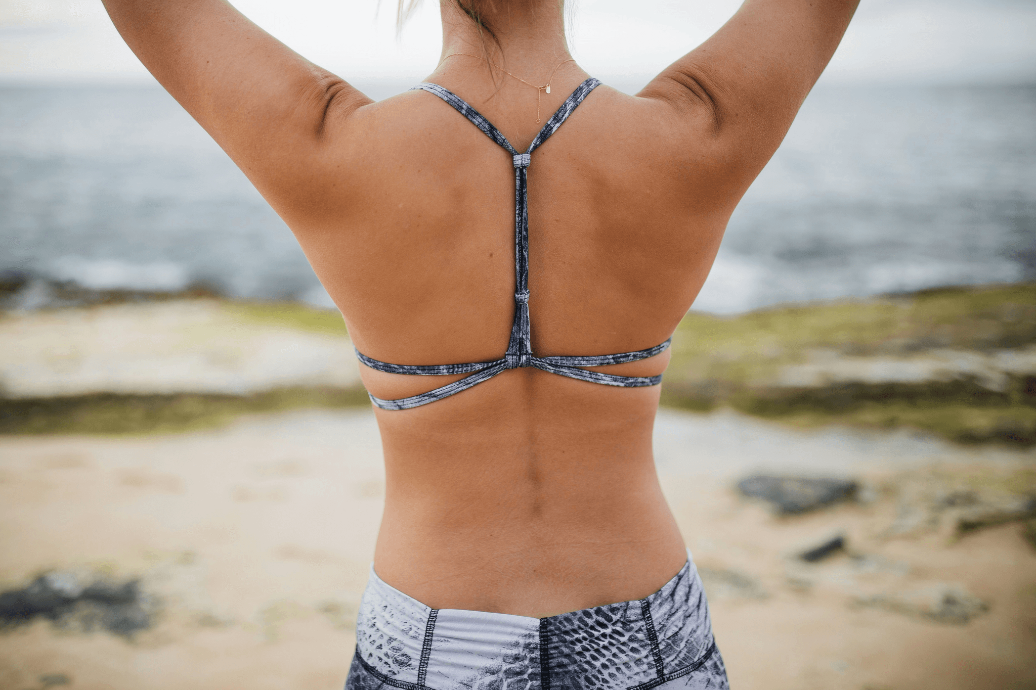 Eine Frau von hinten zu sehen, Rücken, Meer im Hintergrund, sportlich