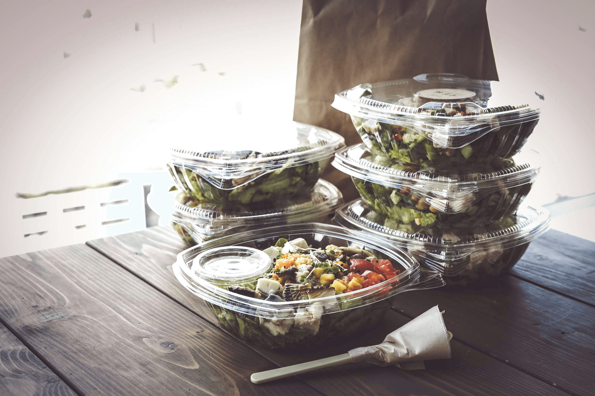 Assorted plastic take out containers with lids showcasing different food items