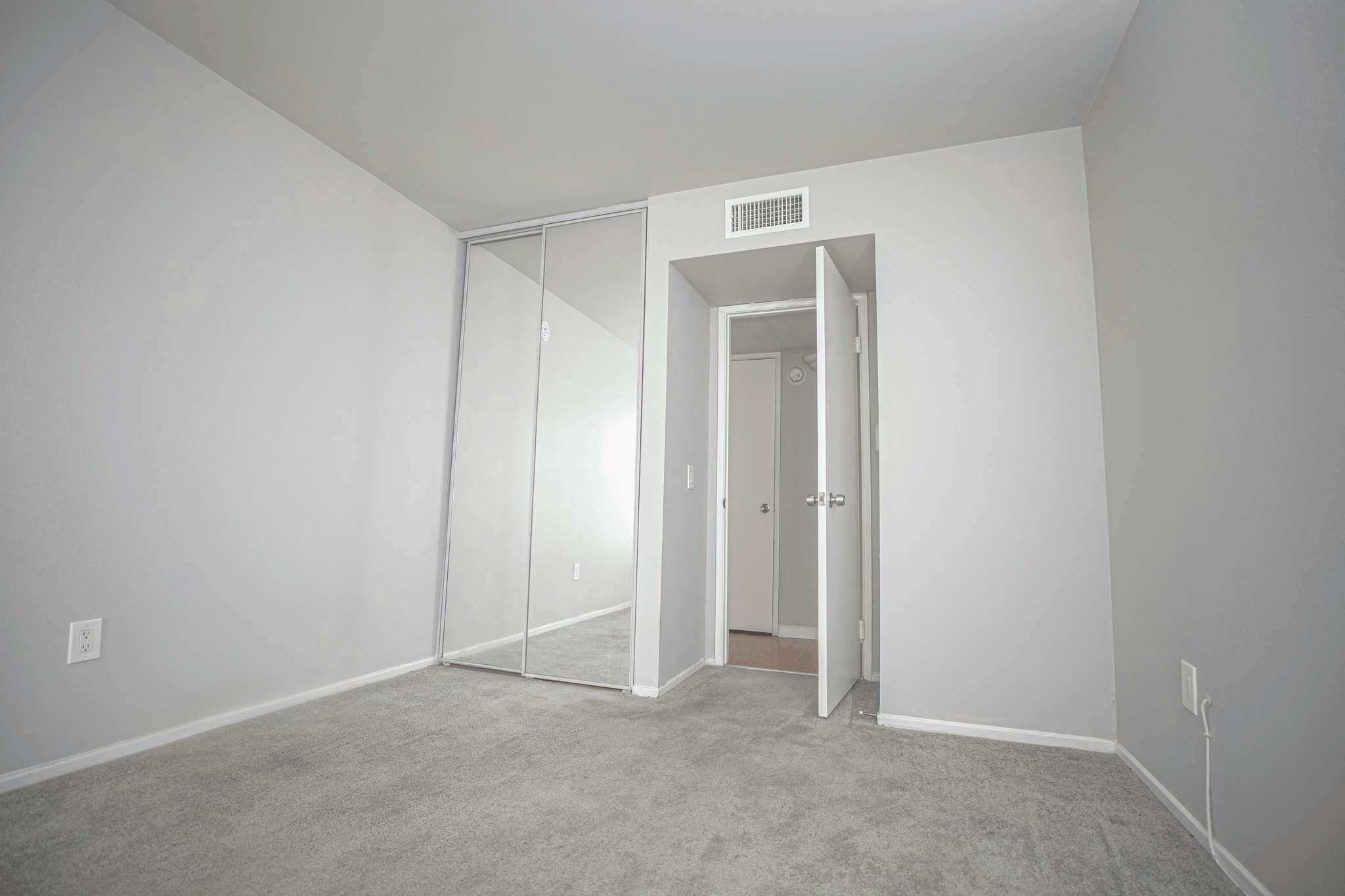 Stylish bedroom with mirrored sliding closet doors reflecting natural light