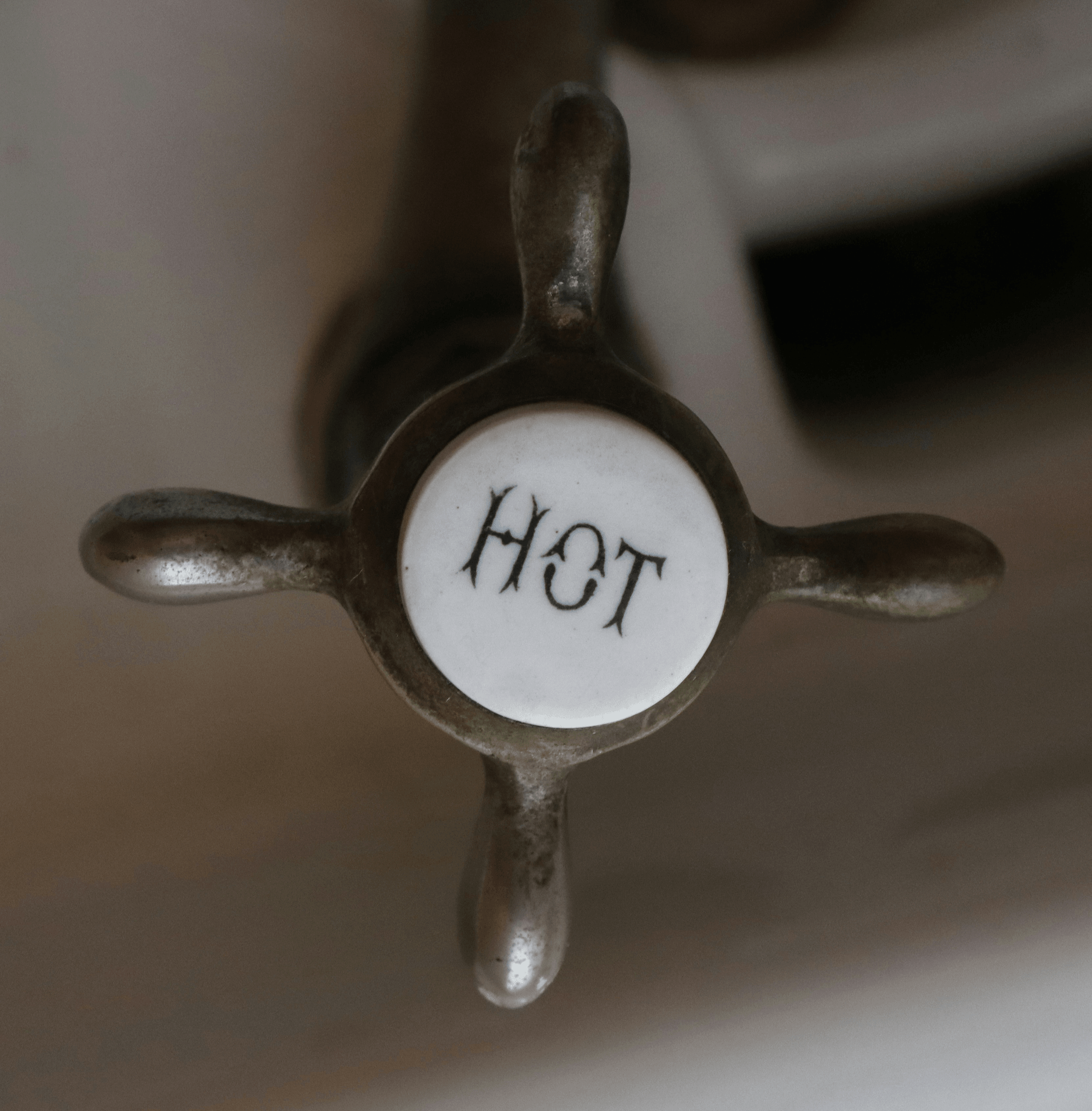 Old style faucet handle with HOT written on a ceramic center. 