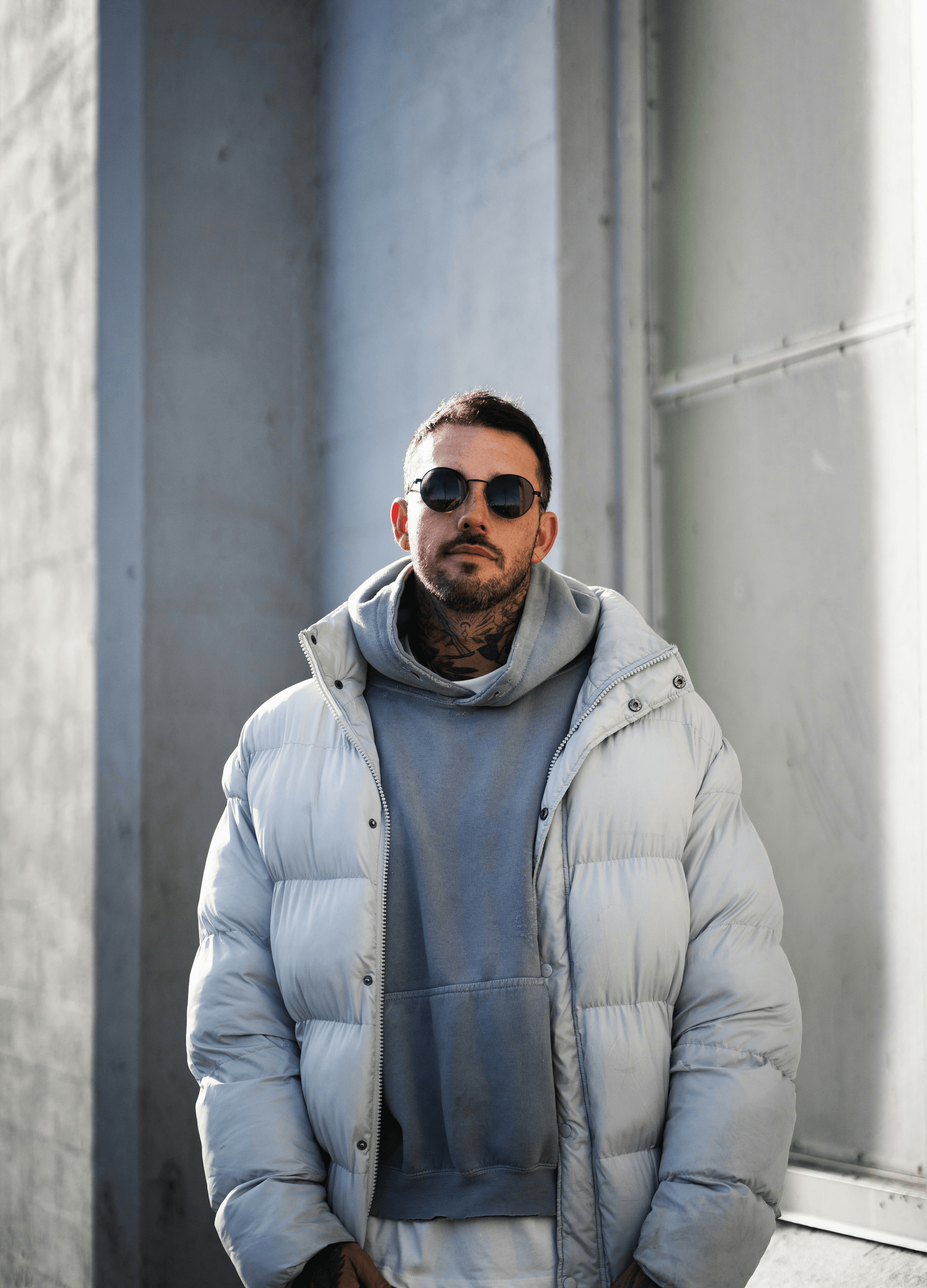 Stylish man showcasing bloc sunglasses against urban backdrop.