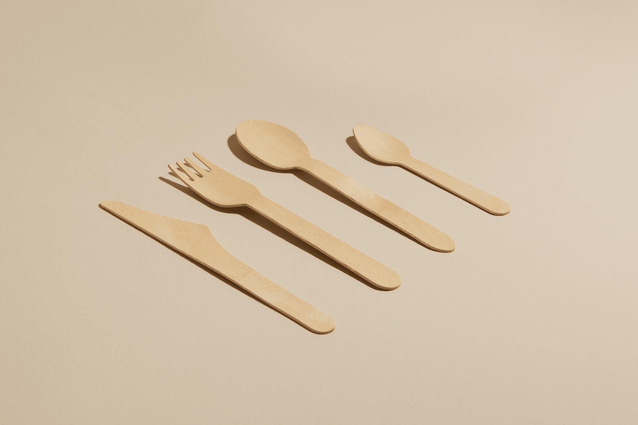 Eco disposable cutlery displayed elegantly on wooden table.