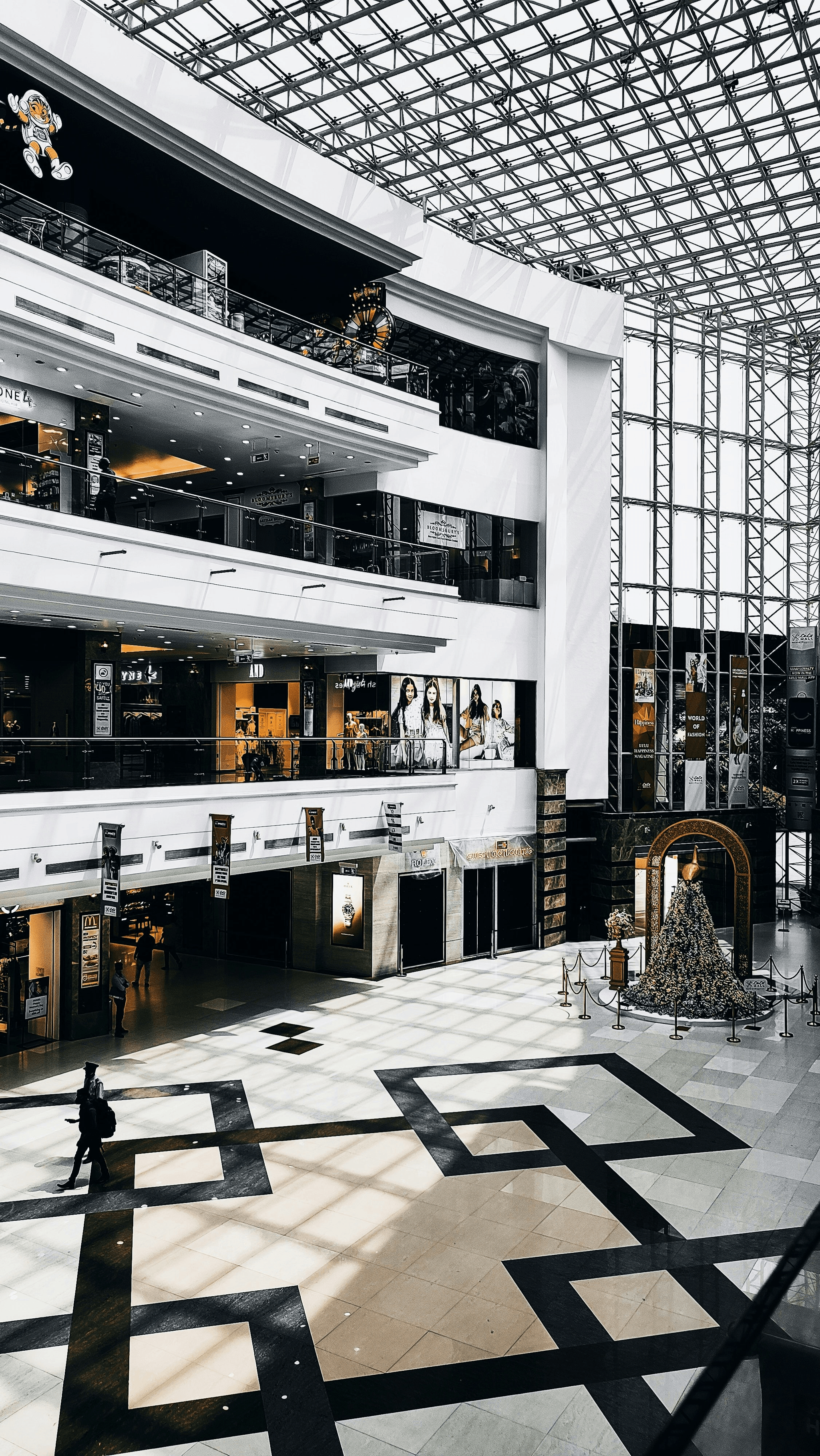 People using a mall escalator inside a modern shopping center.