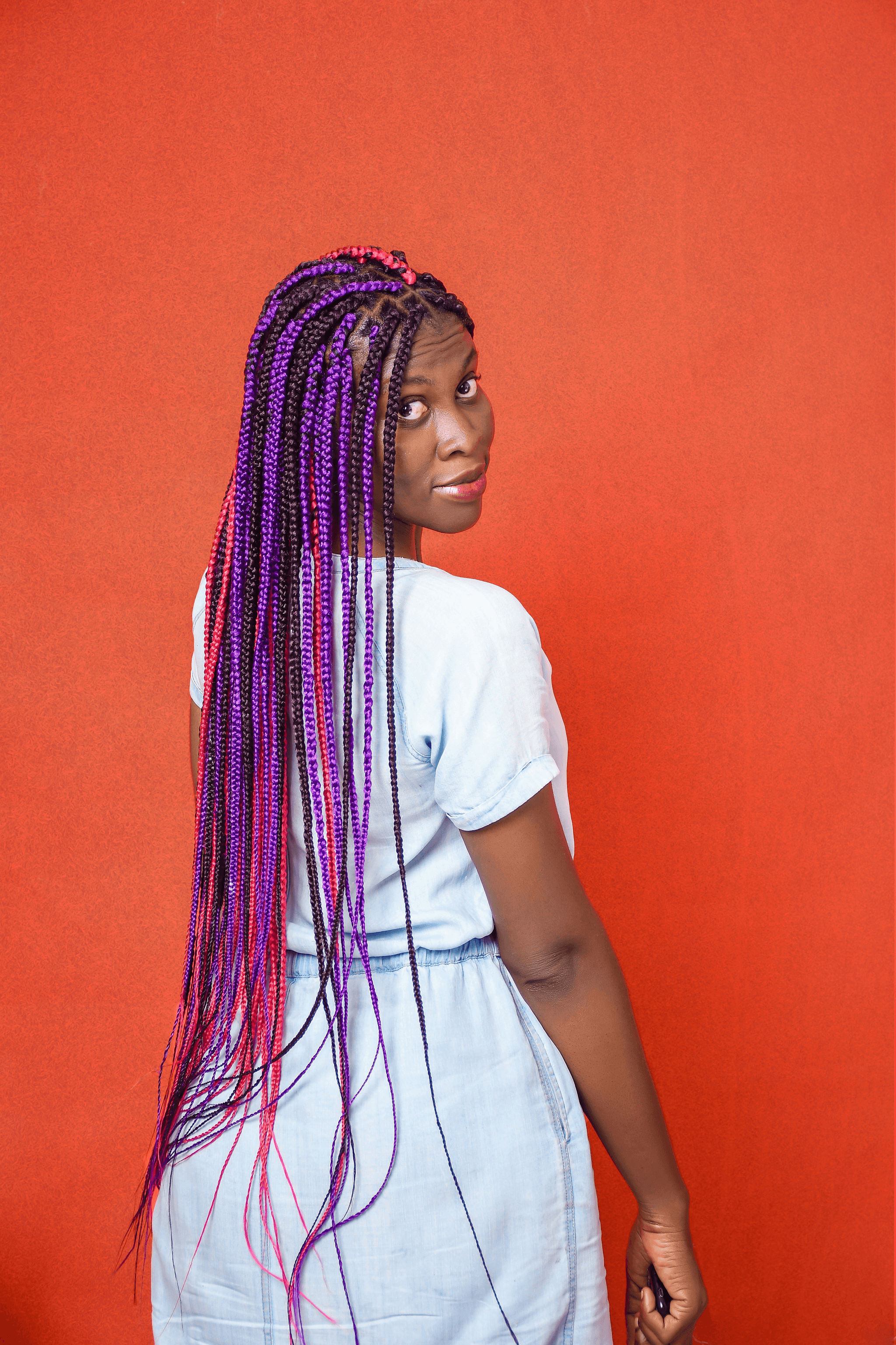 Box Braids with vibrant purple and orange shades on dark skin